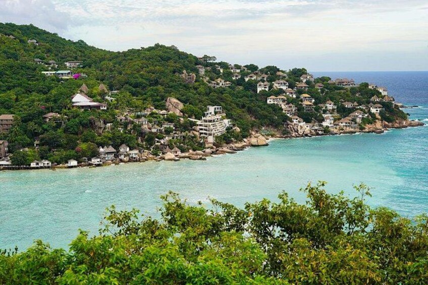 A coastal village with houses on a hillside, a clear blue sea, and lush greenery. 3