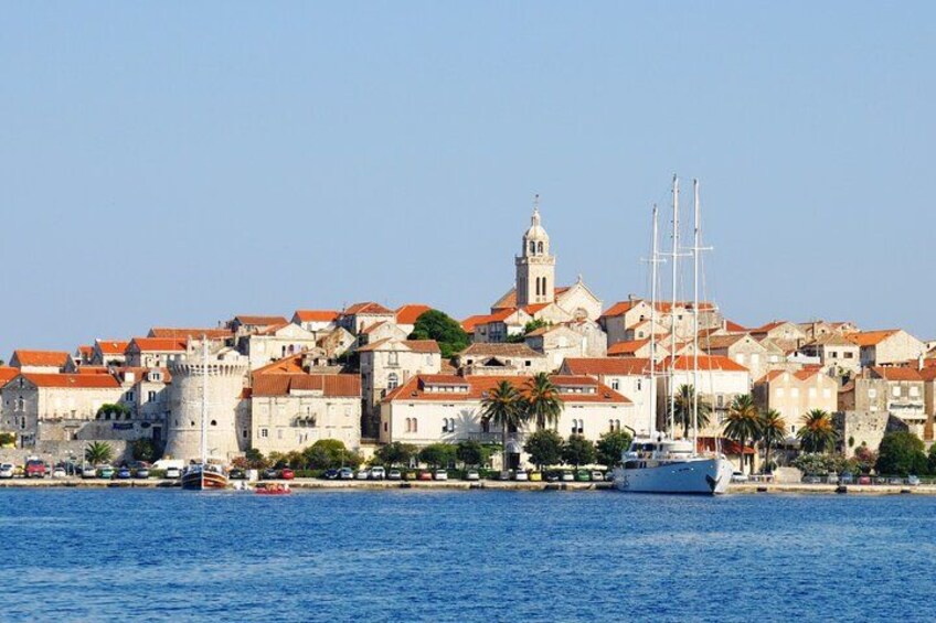 A coastal town with historic buildings, a prominent tower, and a large ship docked at the harbor. 3