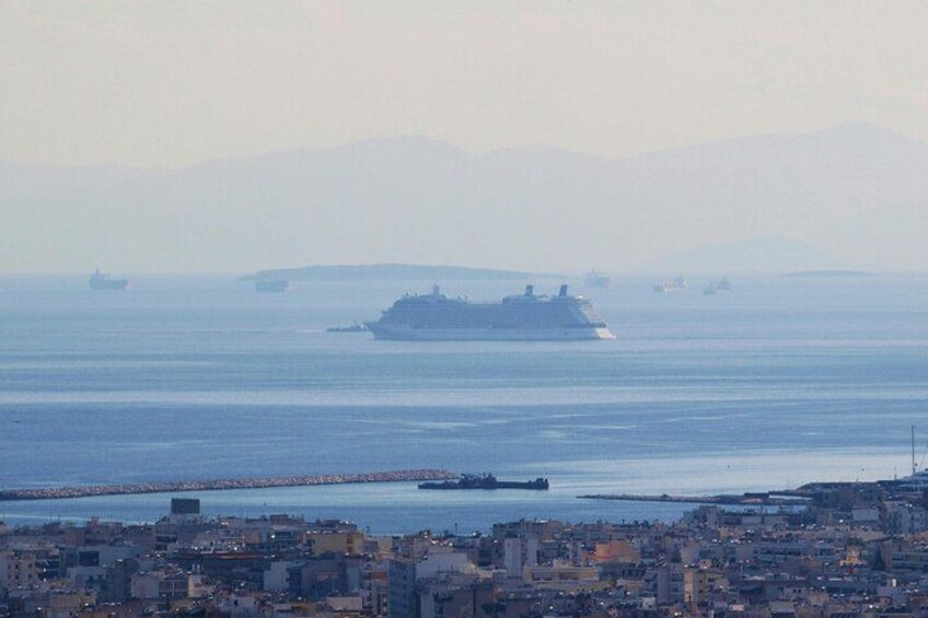 A large cruise ship in the ocean, a cityscape in the foreground, and distant mountains. 4