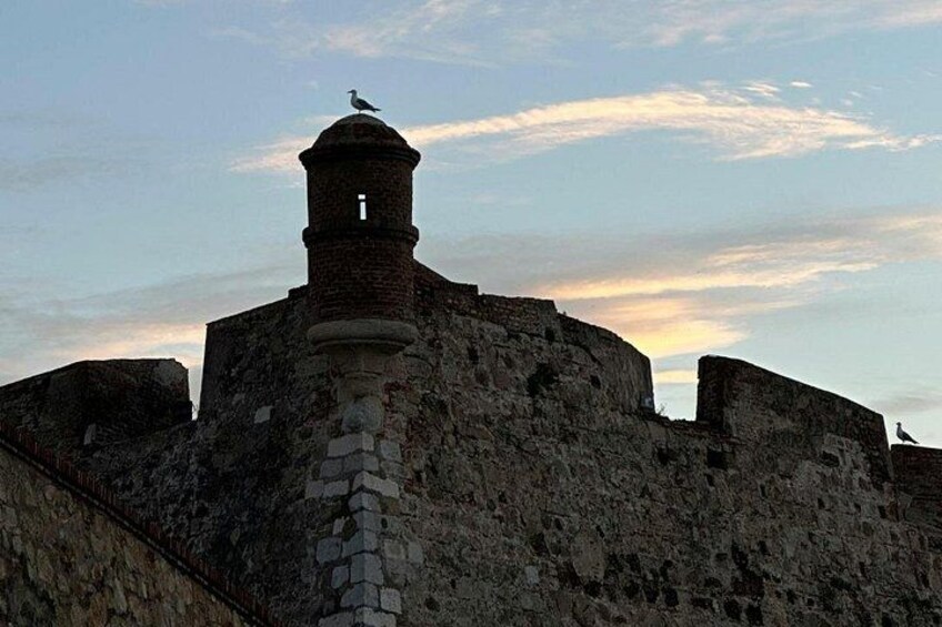 A historical stone structure with a tower and a bird perched on it. 2