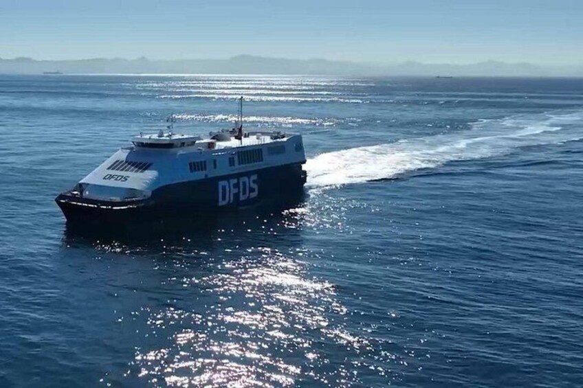 A boat with 'DFDS' on its side moving through the water. 1