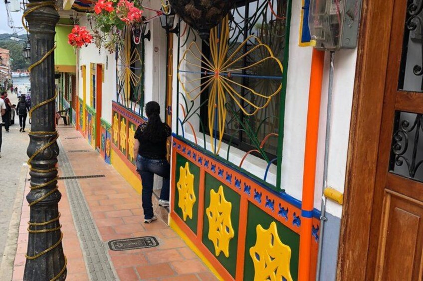 A colorful street with a person walking, decorative window grills, and a metal pole. 3