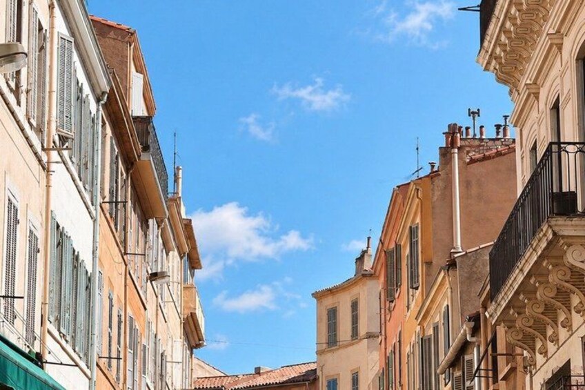 A narrow street between buildings with balconies and shutters. 4
