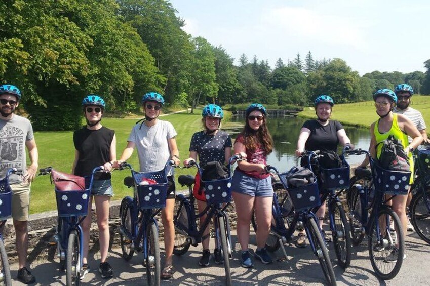 A group of people on bicycles near a body of water with trees in the background. 1