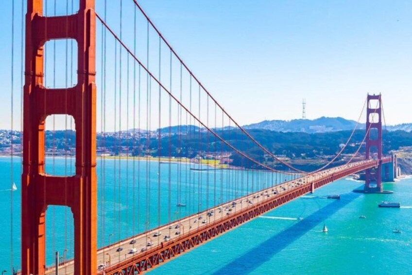 A suspension bridge with a clear view of the water below and distant hills. 1