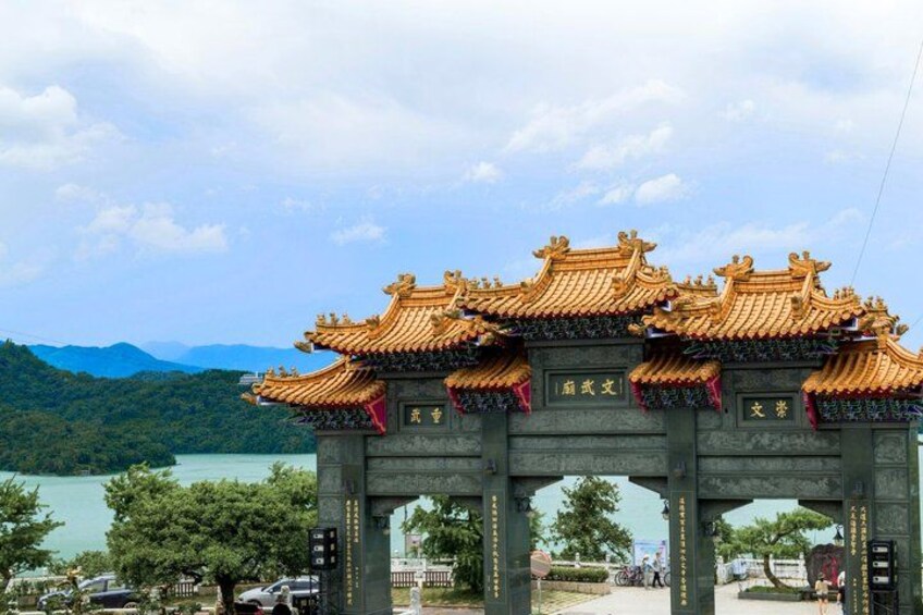 A traditional Chinese gate with ornate roofs, set against a backdrop of mountains and a body of water. 5