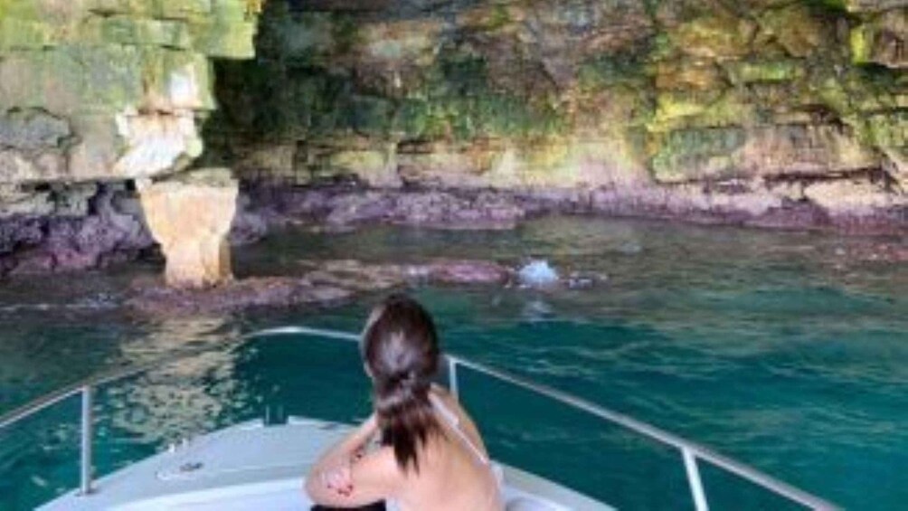 Eine Person auf einem Boot auf dem Wasser, im Hintergrund ein felsiger Klippenhang. 2