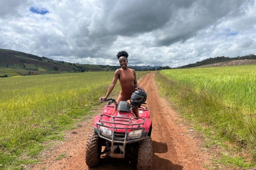 A person on a red ATV in a rural field with a dirt path. 1