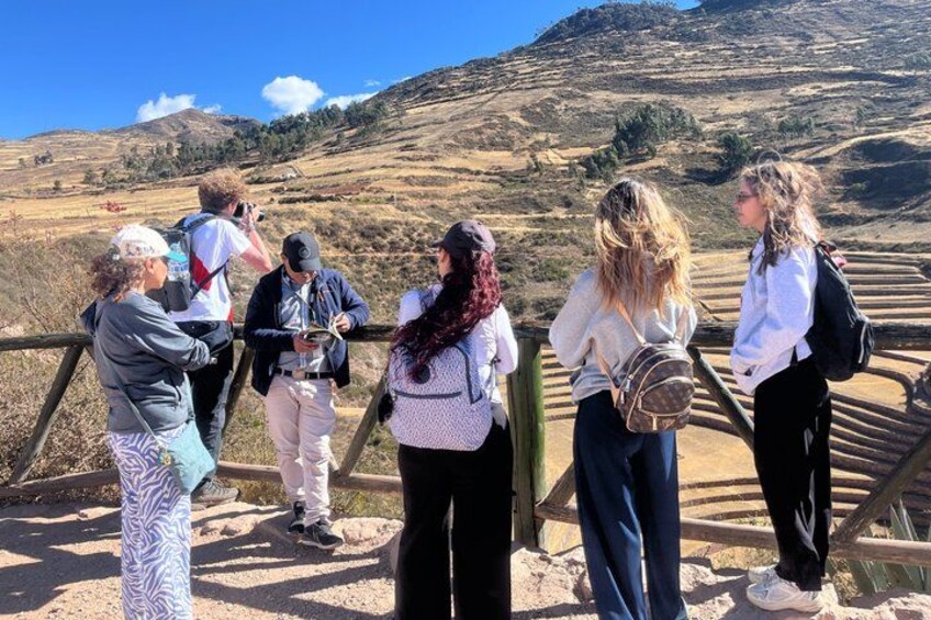 A group of people standing on a wooden bridge overlooking a hilly landscape. 4