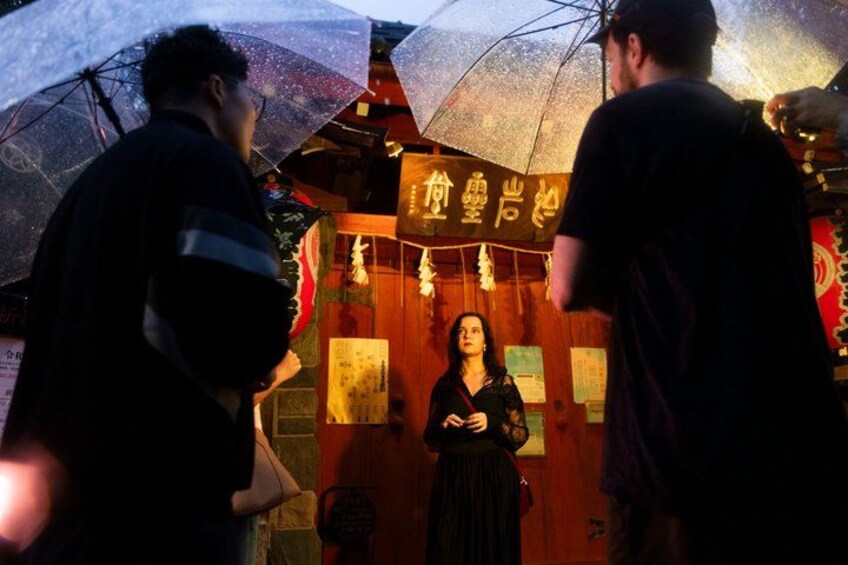 A person standing in front of a traditional building with illuminated signs. 1