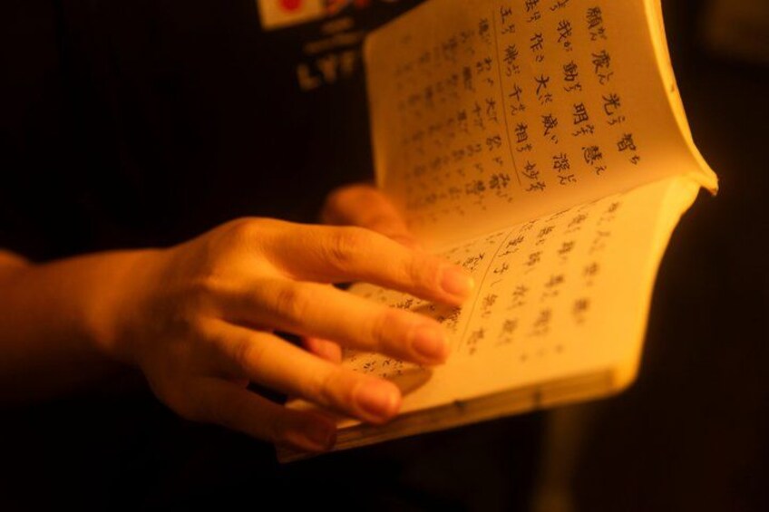 A person holding an open book with handwritten text. 3