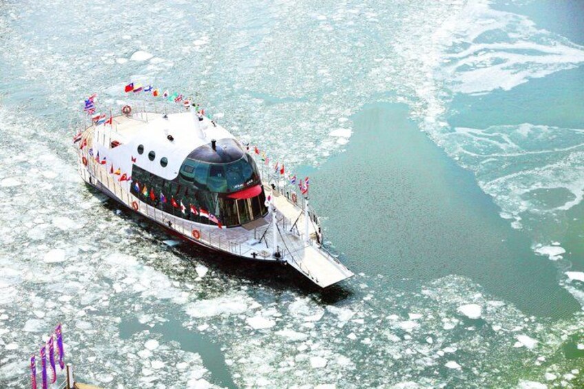 A large, uniquely shaped cruise ship with a pointed bow, sailing on a body of water with ice formations. 2