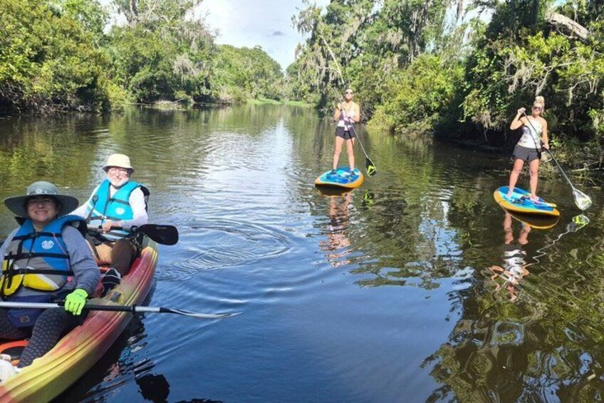 People paddleboarding on a calm river surrounded by dense greenery. 4