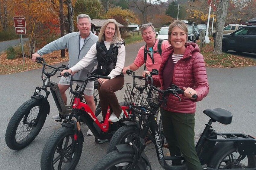 Four people on bicycles, a red bike, and a black bike with a basket. 1