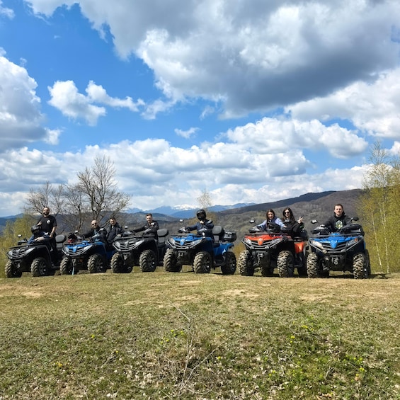 Un grupo de personas en vehículos todo terreno en un campo cubierto de hierba, con montañas al fondo. 3