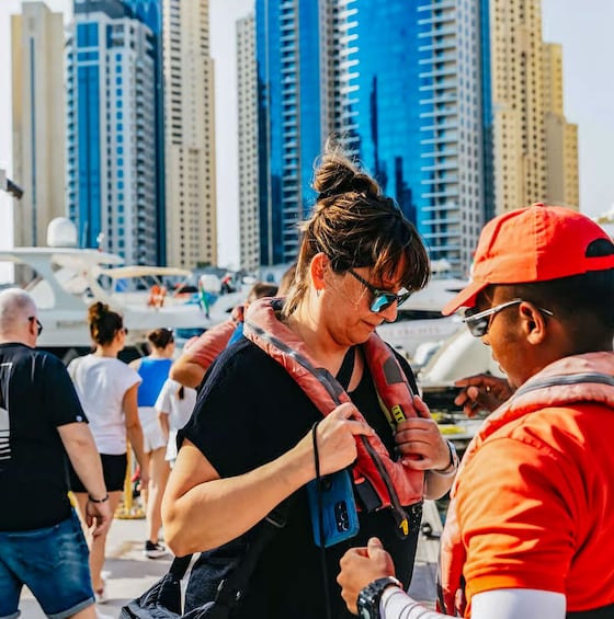 A person wearing a red cap and a black shirt, standing outdoors with high-rise buildings in the background. 3