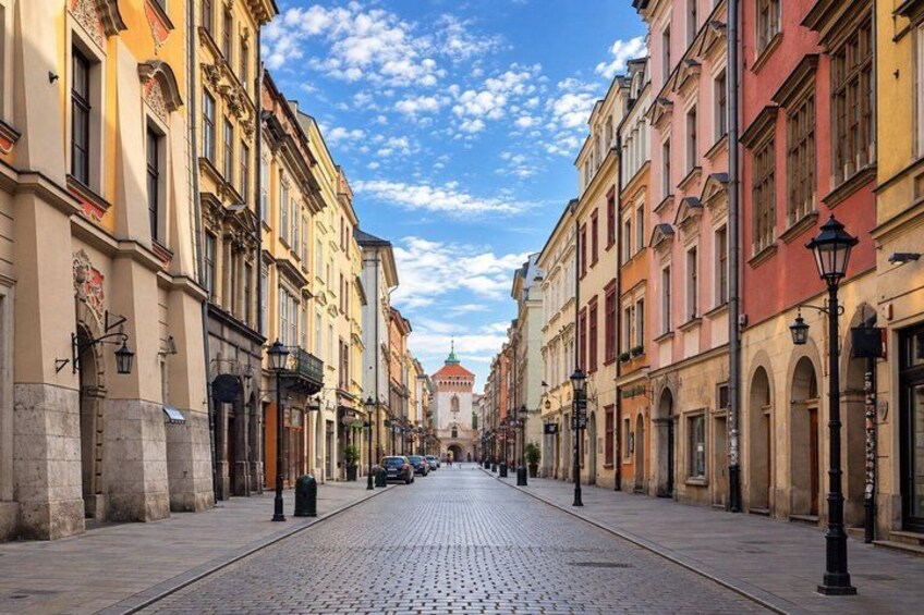 A cobblestone street lined with historic buildings, a clear sky, and a distant church spire. 3