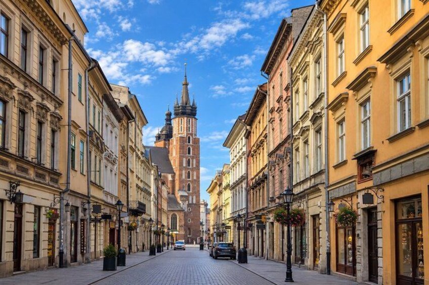 A cobblestone street lined with historic buildings, a prominent church tower, and a clear blue sky. 2