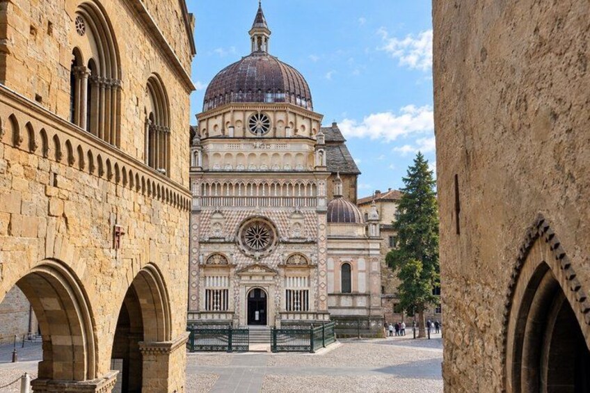 A historic building with a dome, arched windows, and a paved courtyard. 4