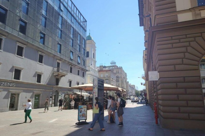 A street with pedestrians, a café, and a building with a sign. 2