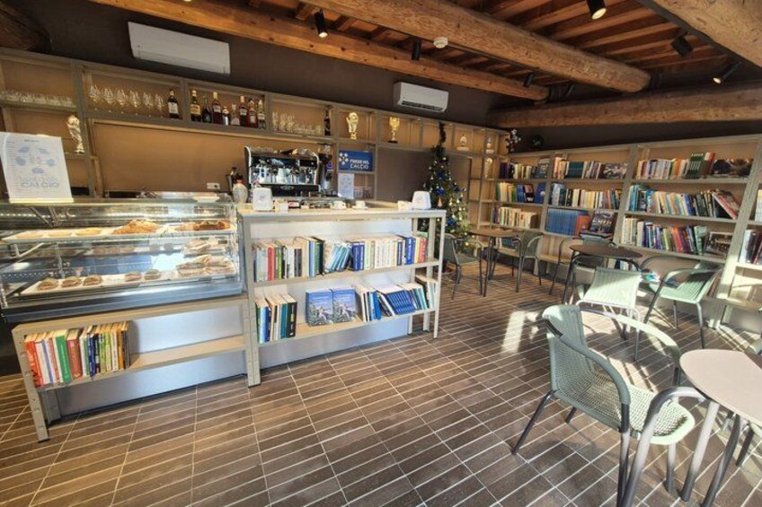 A cozy bookstore with wooden shelves, a coffee station, and a Christmas tree. 5