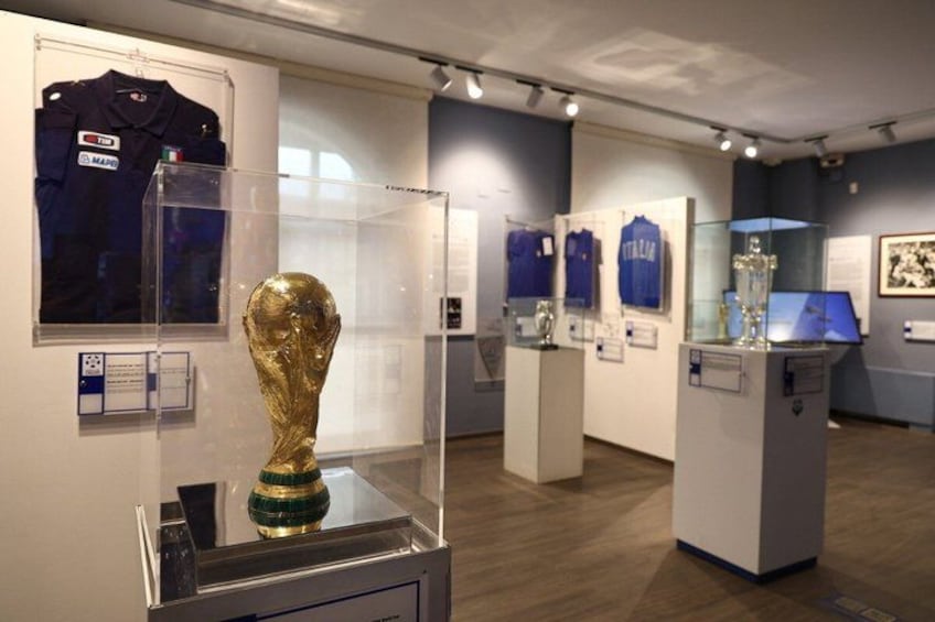 A museum exhibit with a golden trophy, jerseys, and informational plaques. 1