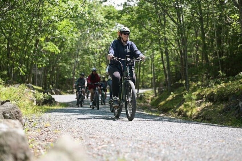 A group of cyclists on a gravel road surrounded by trees. 2