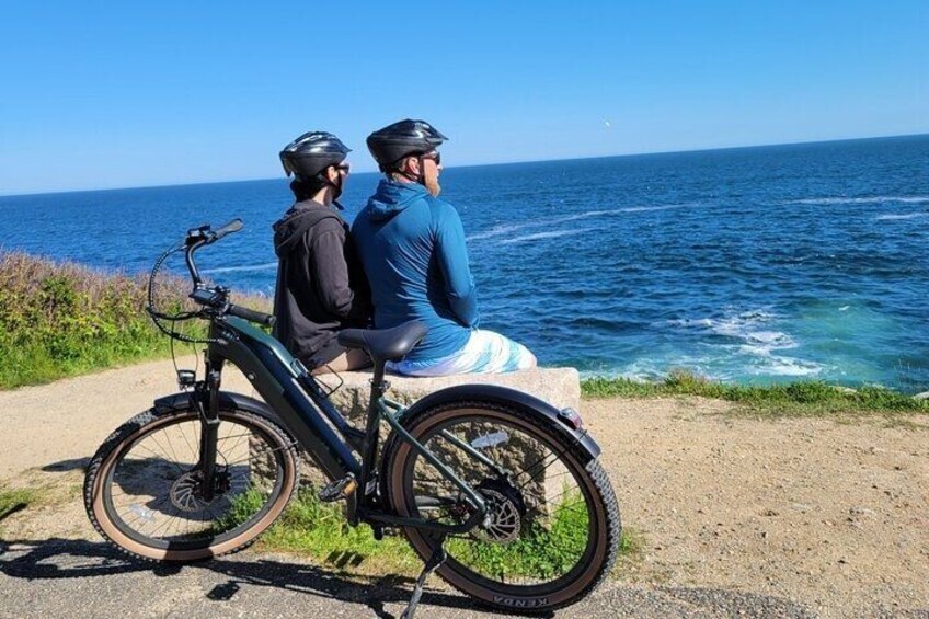 Two people on a tandem bike by the sea. 1
