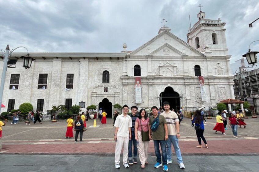 A group of people standing in front of a historic building with a bell tower. 3