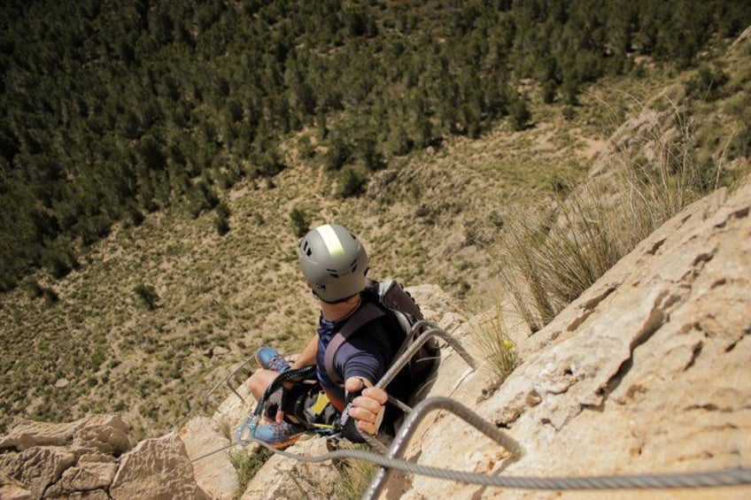 A person rappelling down a rocky cliff with a helmet and harness. 4