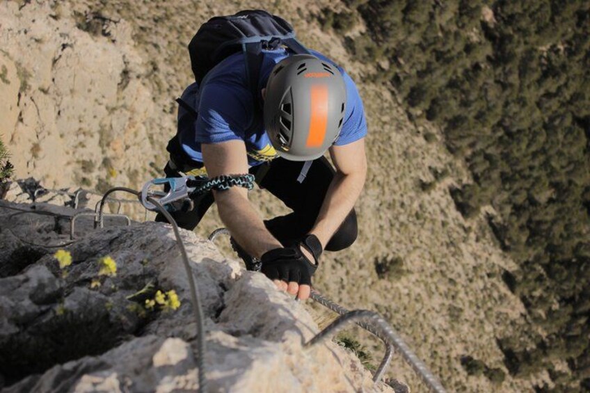 A person climbing a rocky mountain with a helmet and harness. 2