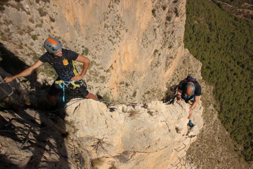 Two individuals rappelling down a steep cliff. 1