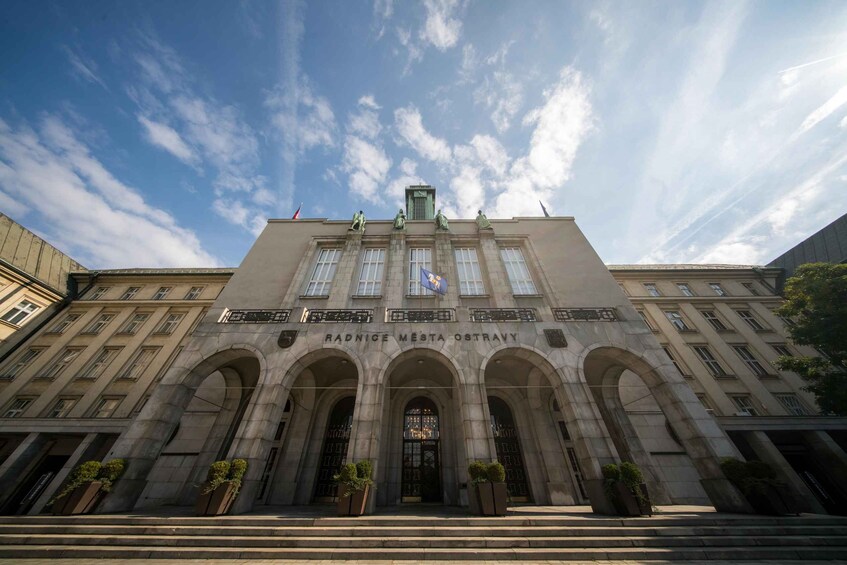 A large, historic building with arched entrances and statues on the roof. 1
