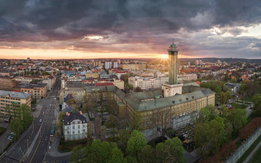 A cityscape with a prominent tower, a mix of residential and commercial buildings, and a sunset sky. 5