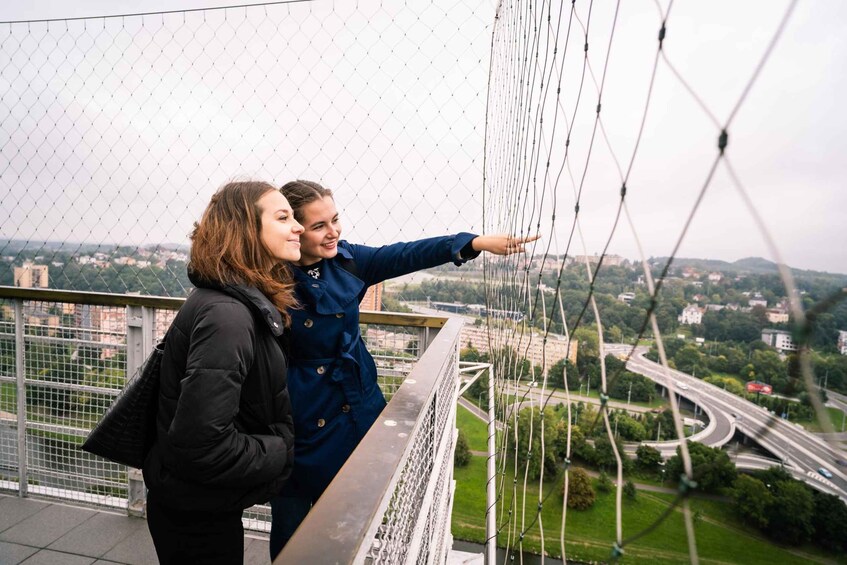 Two people standing on a bridge with a cityscape in the background. 4