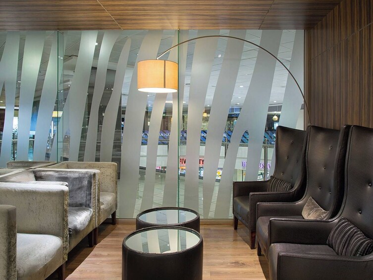 A modern lounge area with leather sofas, round glass tables, and a unique curved glass partition. 3