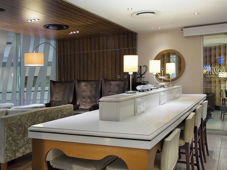 A modern lounge with leather seating, a long counter, and wall-mounted lamps. 4