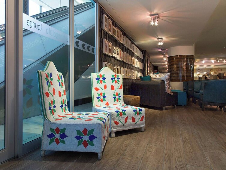 A modern interior with two patterned armchairs, a staircase, a bookshelf, and a counter. 1
