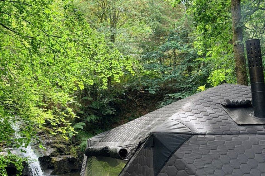 A house with a hexagonal roof, surrounded by dense green forest and a small waterfall. 5