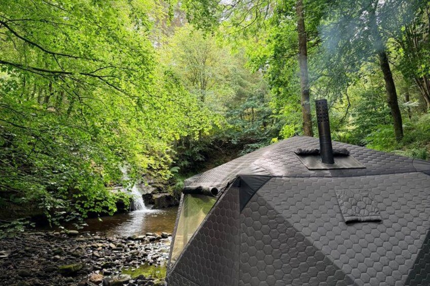 A house with a hexagonal roof, a chimney, and a stream in a forest. 4