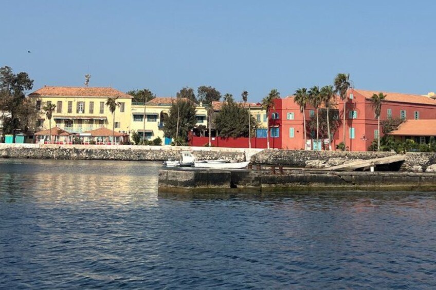 A waterfront with colorful buildings, a small boat, and a clear blue sky. 2