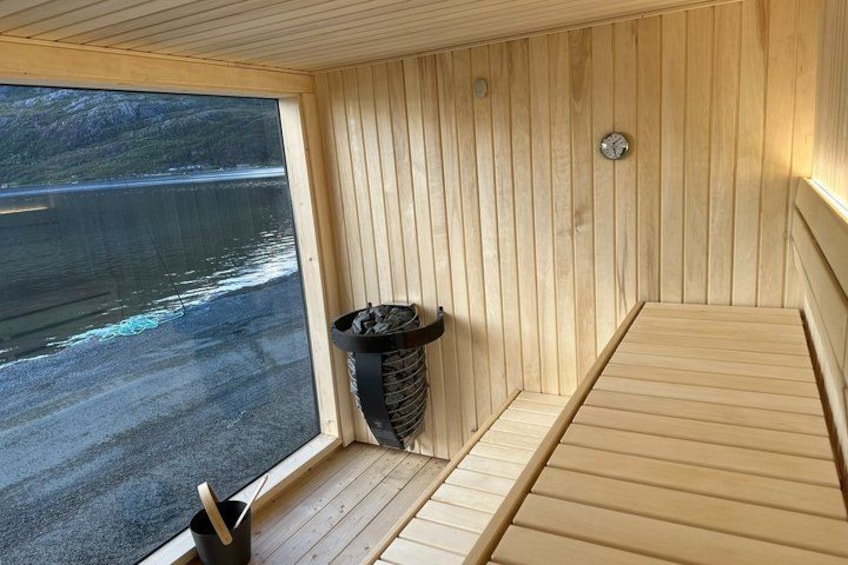A wooden sauna with a window overlooking a lake. 1