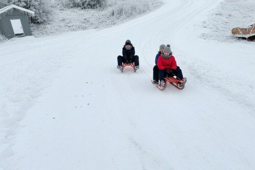 Two children sledding down a snowy hill. 4