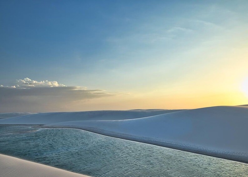 A desert landscape with sand dunes and a body of water. 3
