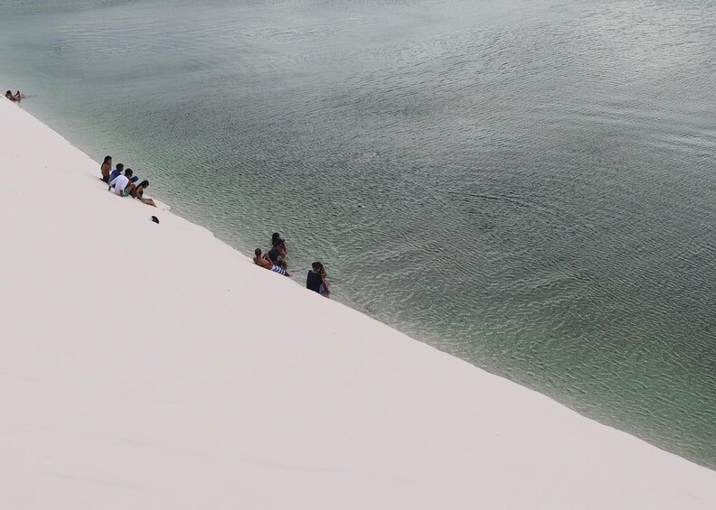A sandy beach with people sitting and relaxing by the water. 5