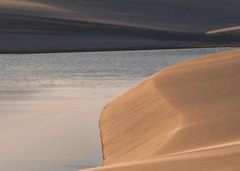 A desert landscape with sand dunes and a body of water. 2