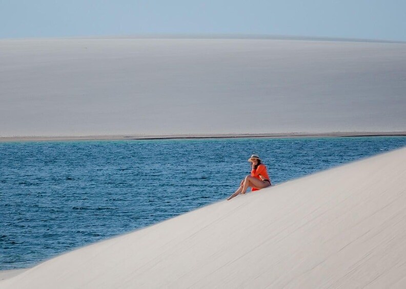 A person sitting on a sand dune by the sea. 1