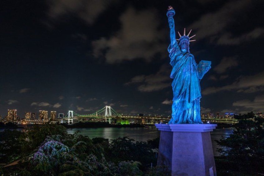 A nighttime view of the Statue of Liberty with the Brooklyn Bridge in the background. 3