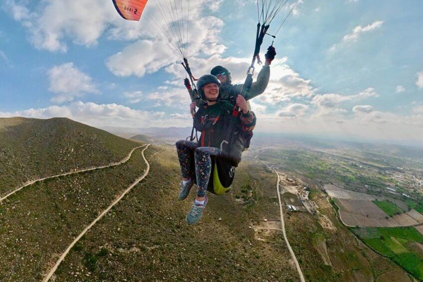 A person paragliding over a mountainous landscape with a clear sky. 3