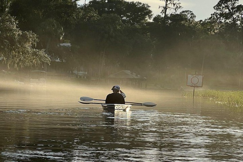 A person kayaking on a misty river surrounded by trees. 2